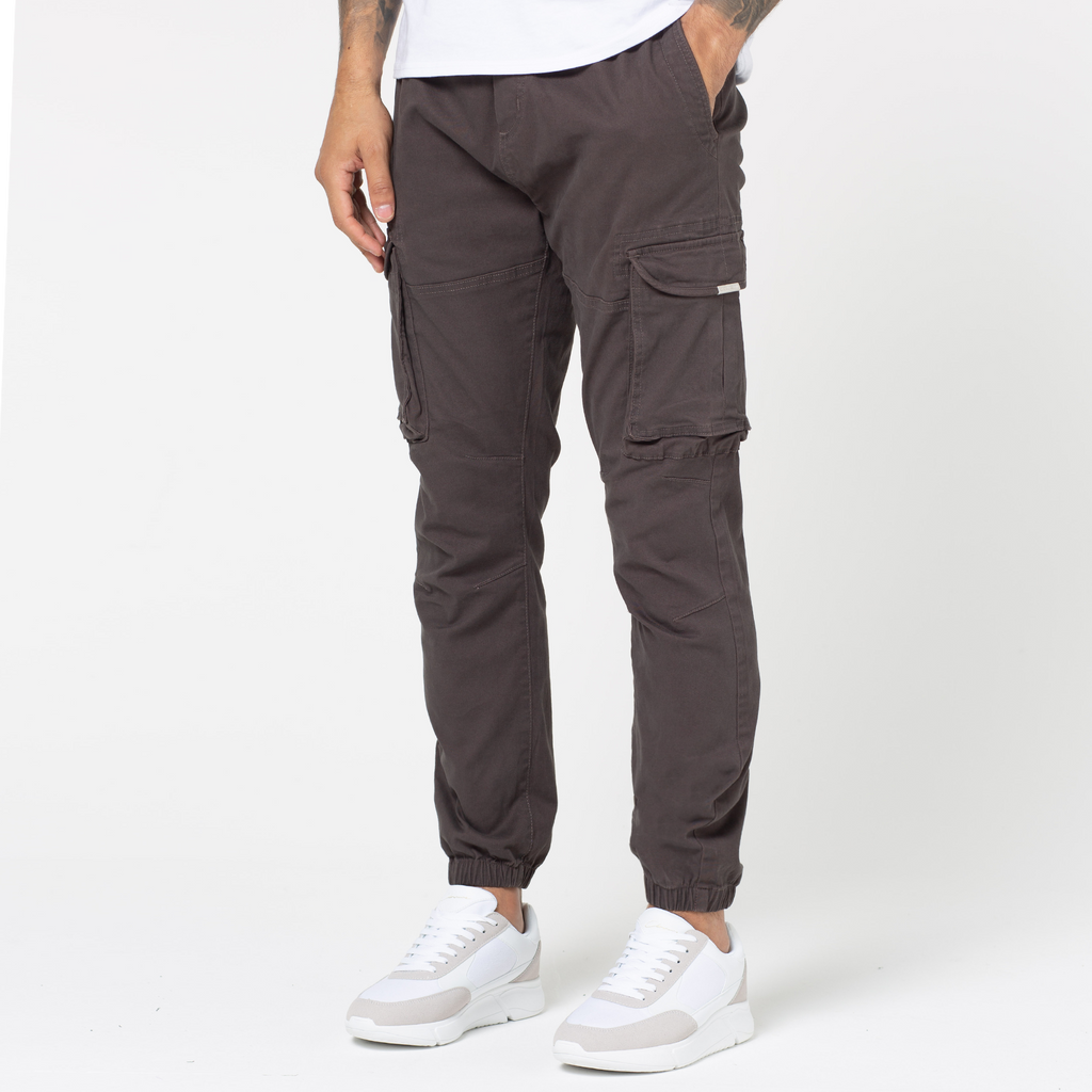 Man wearing utility cargo pant in colour brown with pocks and cuffed ankles