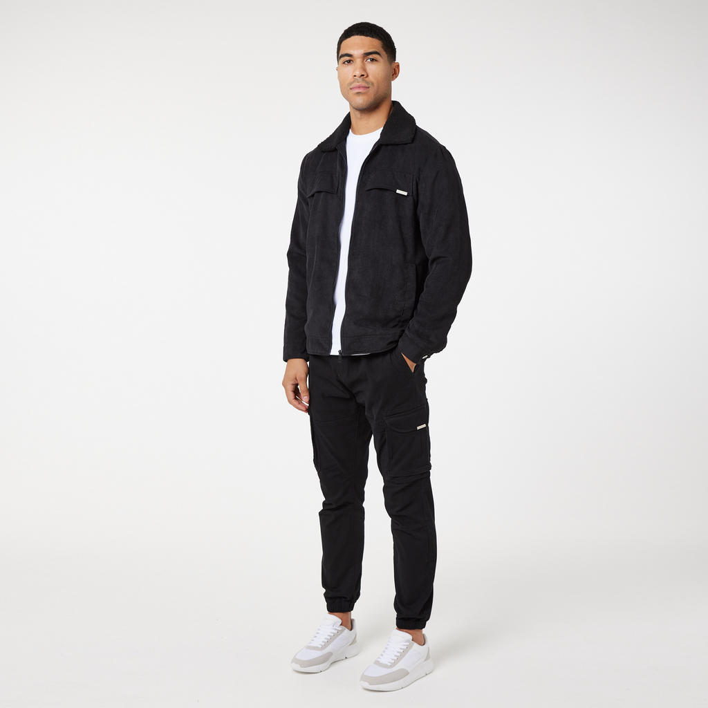model wearing black corduroy overshirt with black cargo pants and white shoes