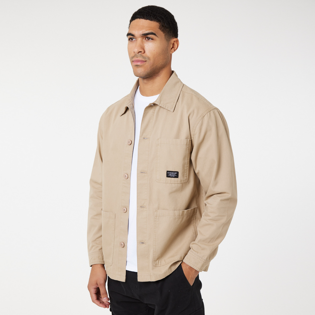 Model wearing stone chore overshirt jacket with buttons and white top underneath