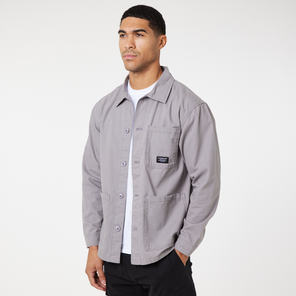 Men's mid grey overshirt jacket with grey buttons and black logo paired with a white top