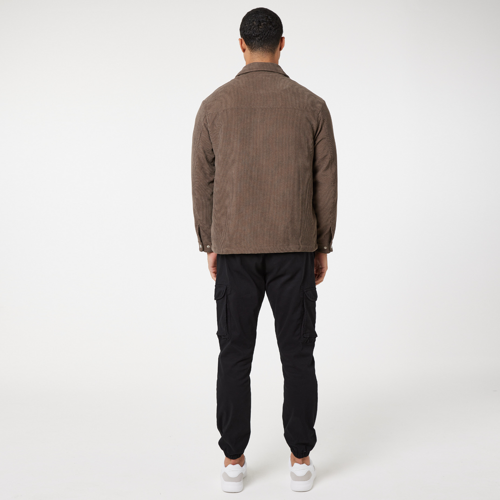 Back view of men's corduroy overshirt in brown and black cargo pants