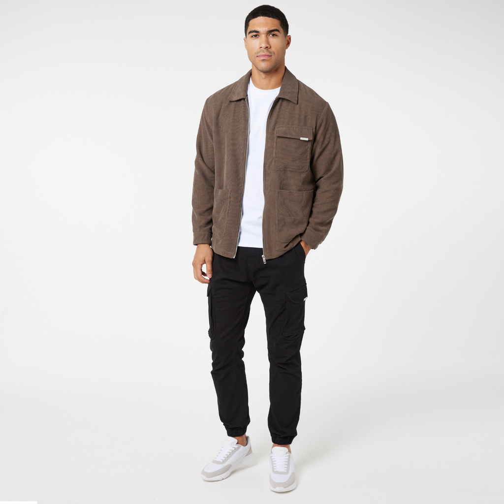Corduroy overshirt unzipped in brown paired with white top and black cargo trousers