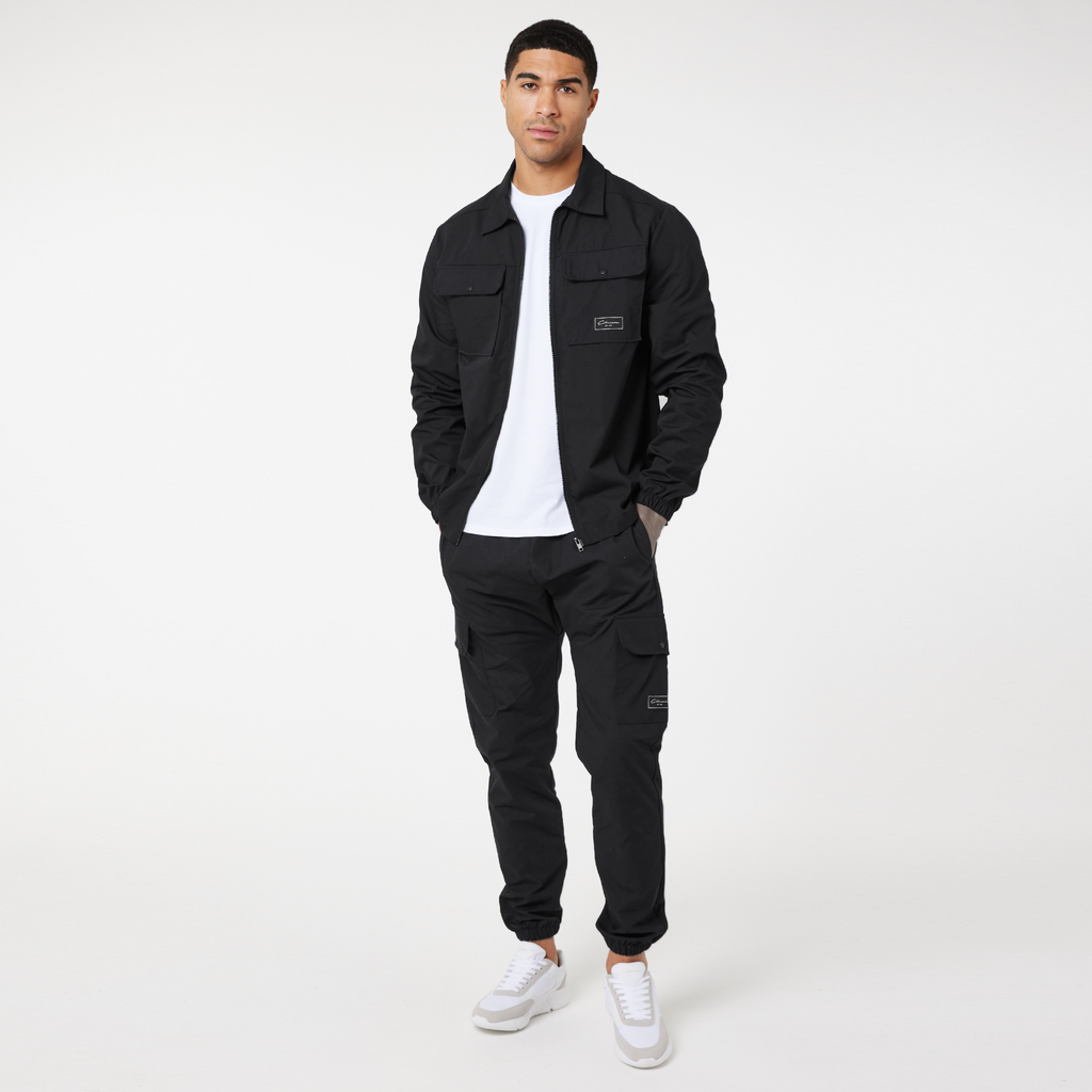 Black zip overshirt styled with white top, black cargo pants and trainers
