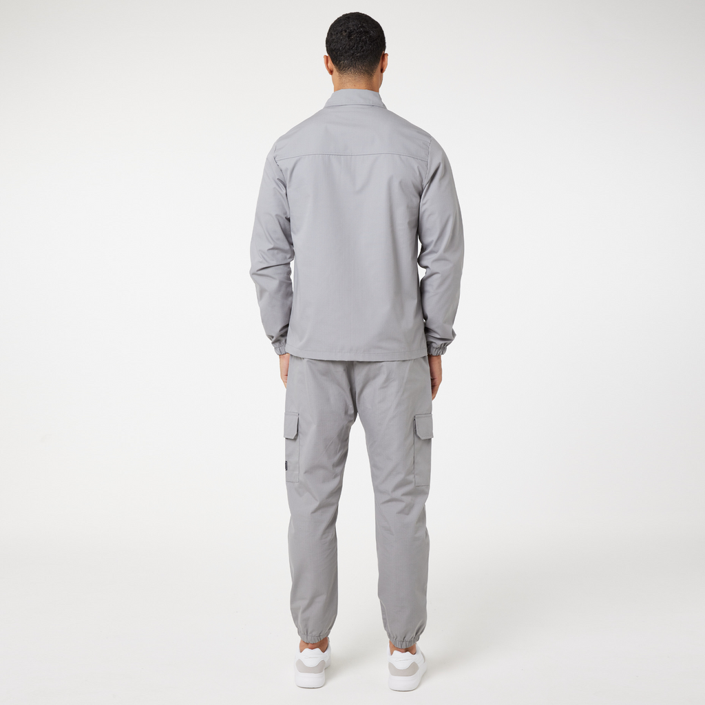 Back profile of ice grey utility overshirt, cargo pants and white trainers
