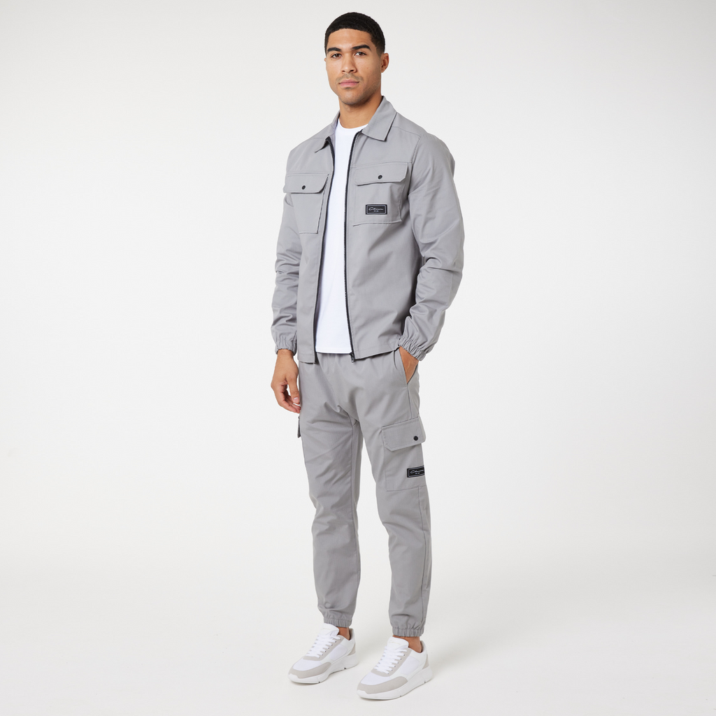 Models wearing full men's cargo twinset in ice grey with white and grey casual trainers