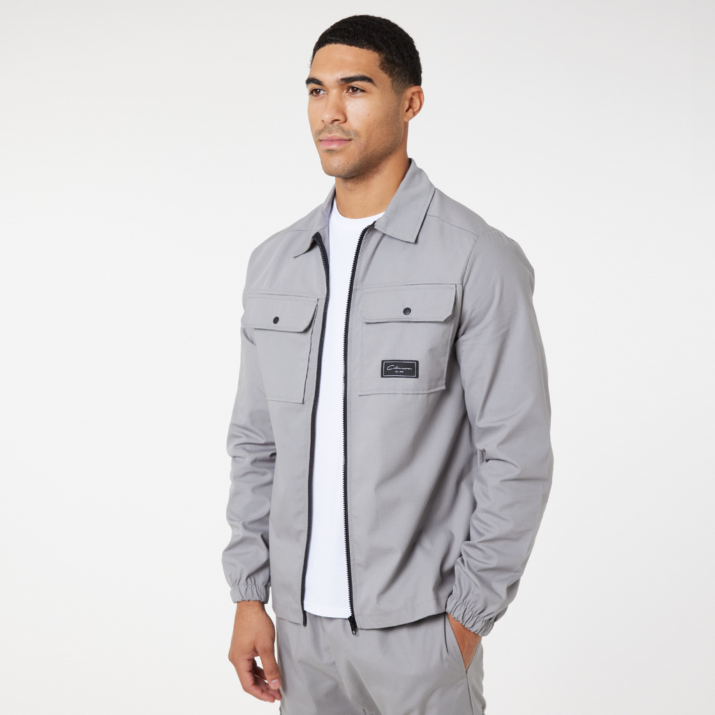 Model wearing ice grey utility overshirt jacket with black zip and black "Closure" logo on overshirts pocket