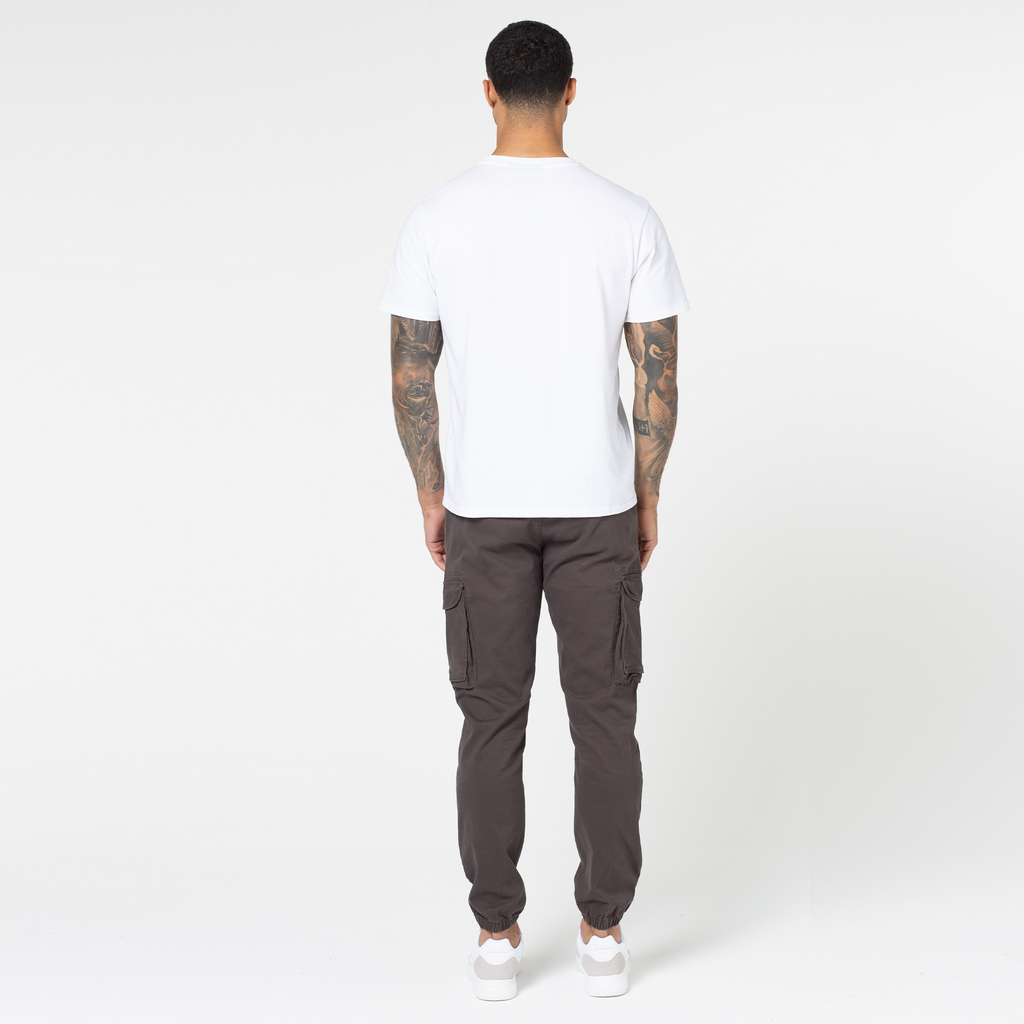 Back profile of model wearing ash brown utility cargo pants with white top