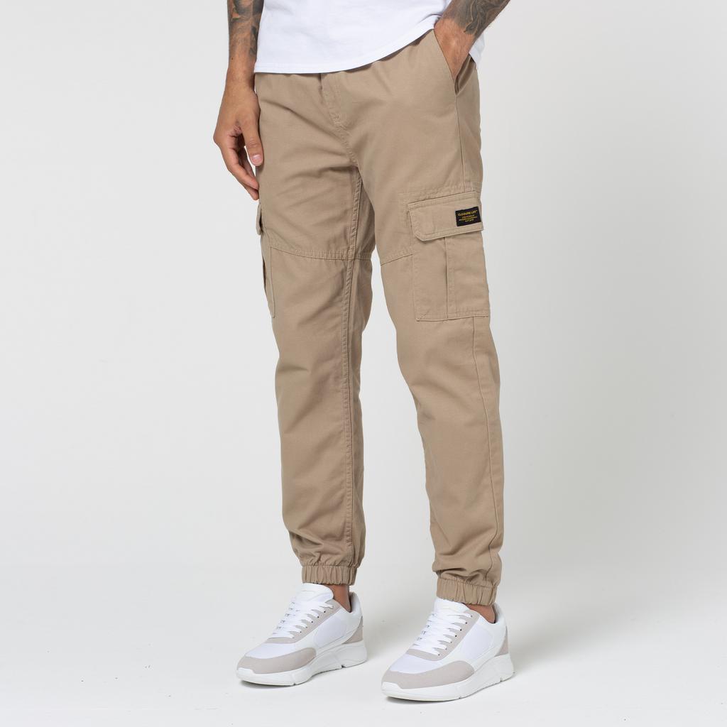 Model wearing beige cuffed utility cargo pants with white trainers