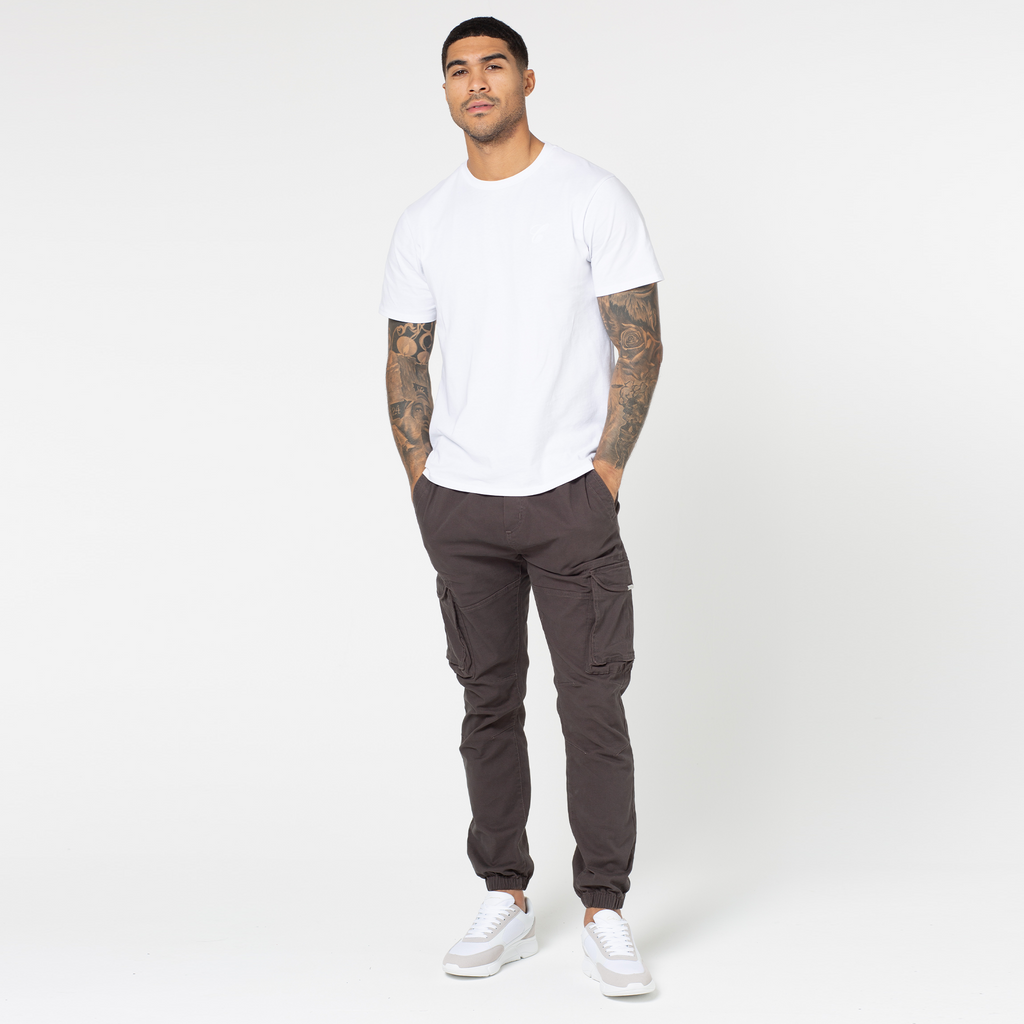 model showing full outfit of ash brown cargo pants pared with mens tee and white trainers
