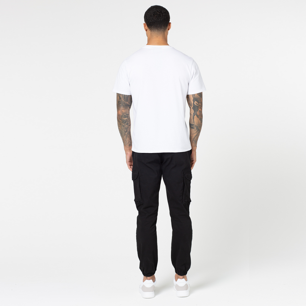 back profile of model wearing black affordable cargo pants with back of plain white top and men's trainers