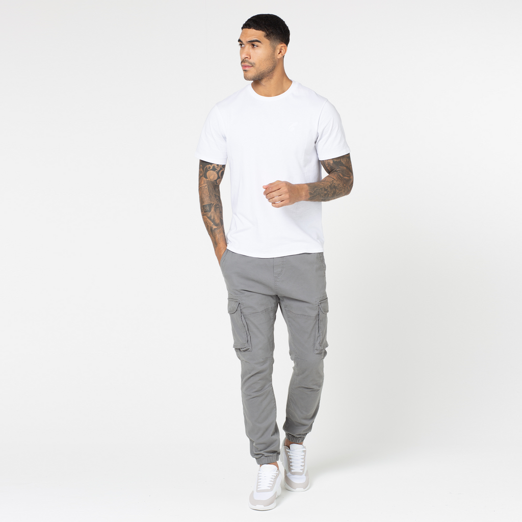 Man styled a pair of utility trousers in grey with white and grey trainers and white short sleeve top
