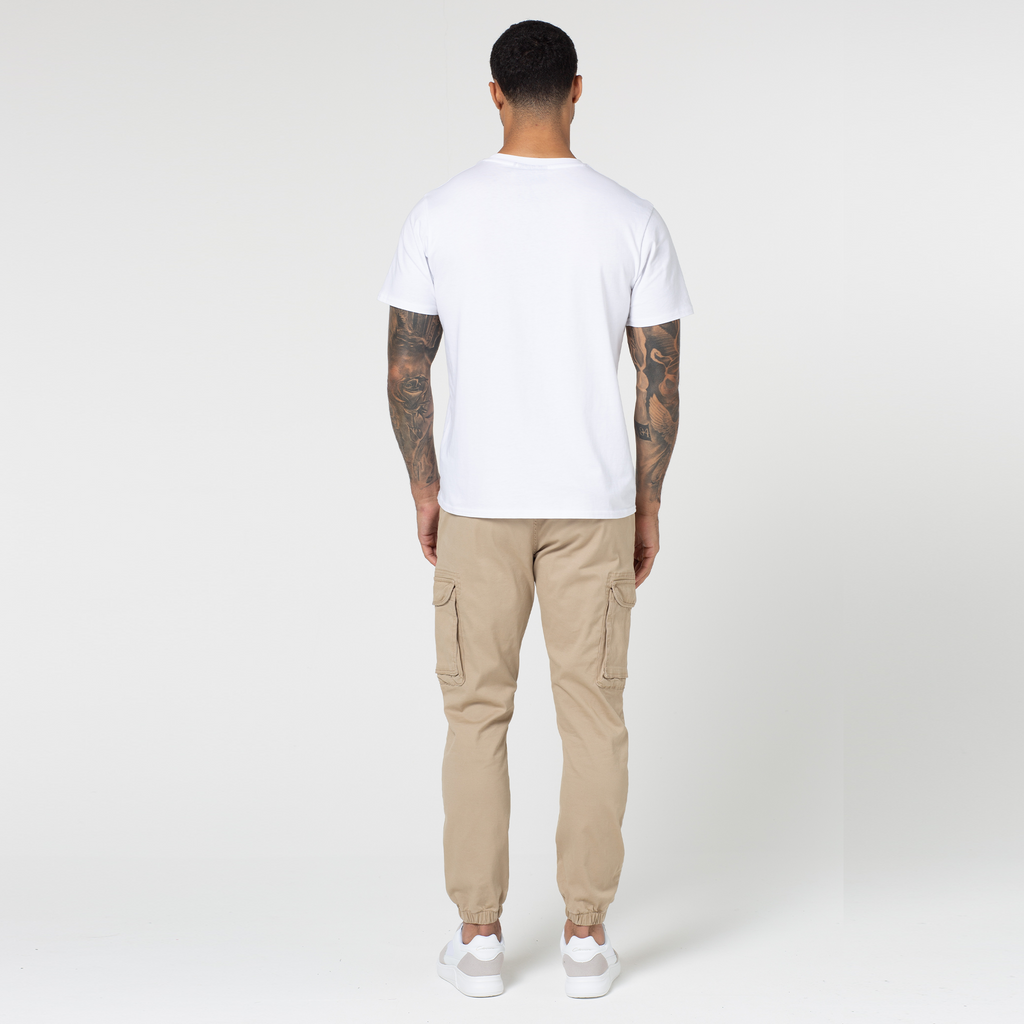 Model's back profile while wearing stone men's cargo trousers with men's white tee and trainers