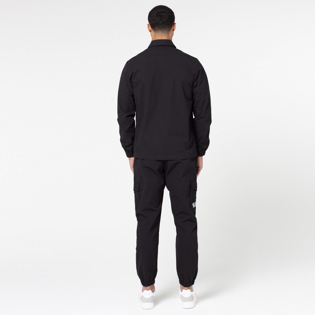 back profile of black utility trousers and matching men's overshirt