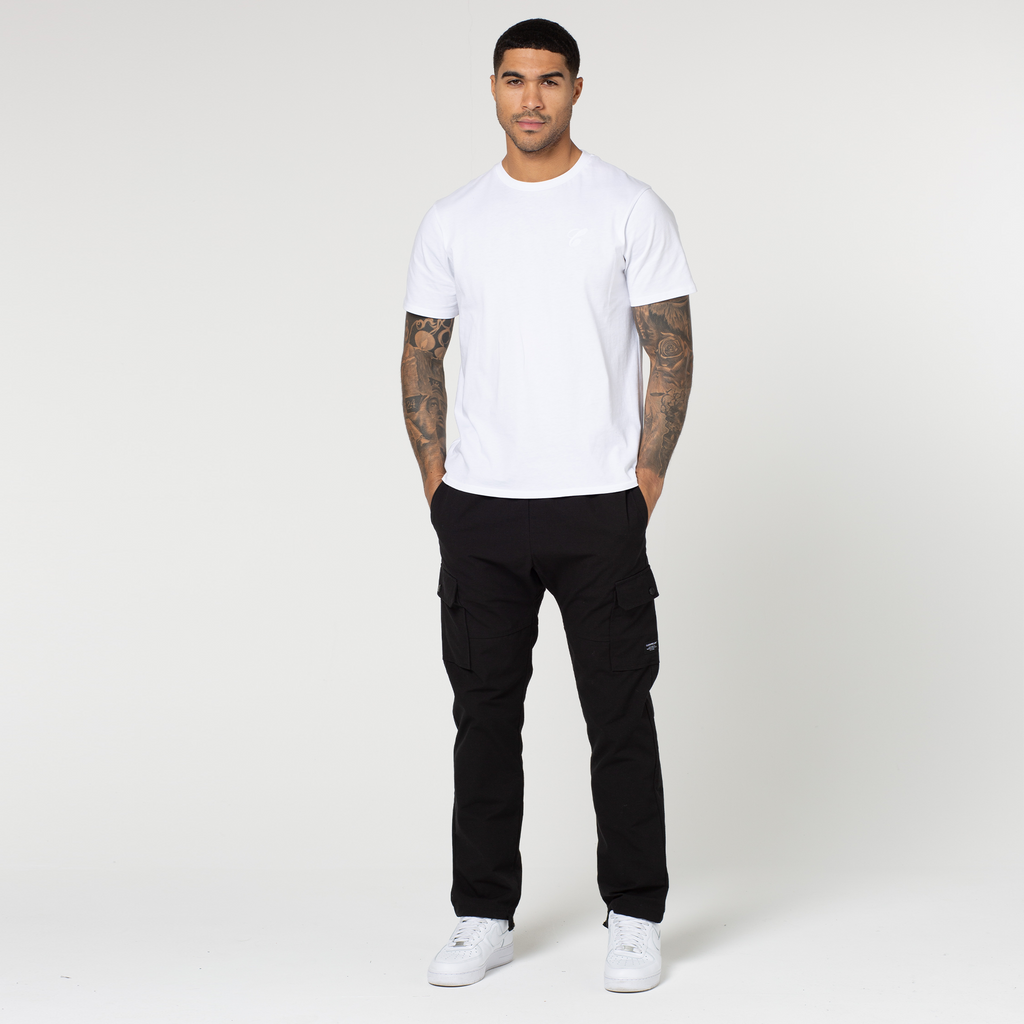 Model wearing open hem black utility trousers styled with white trainers and tee