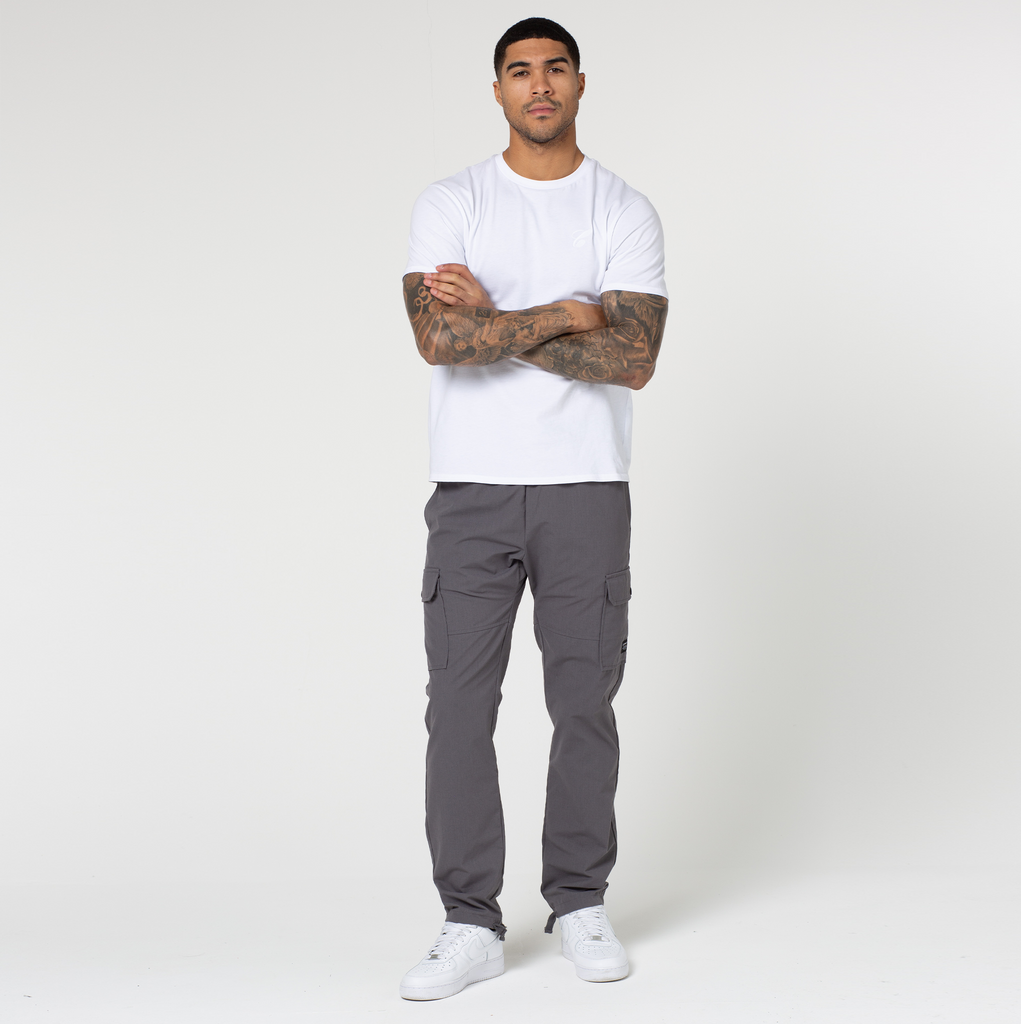 Model crossing his arm while wearing dark grey utility cargo pants and white top