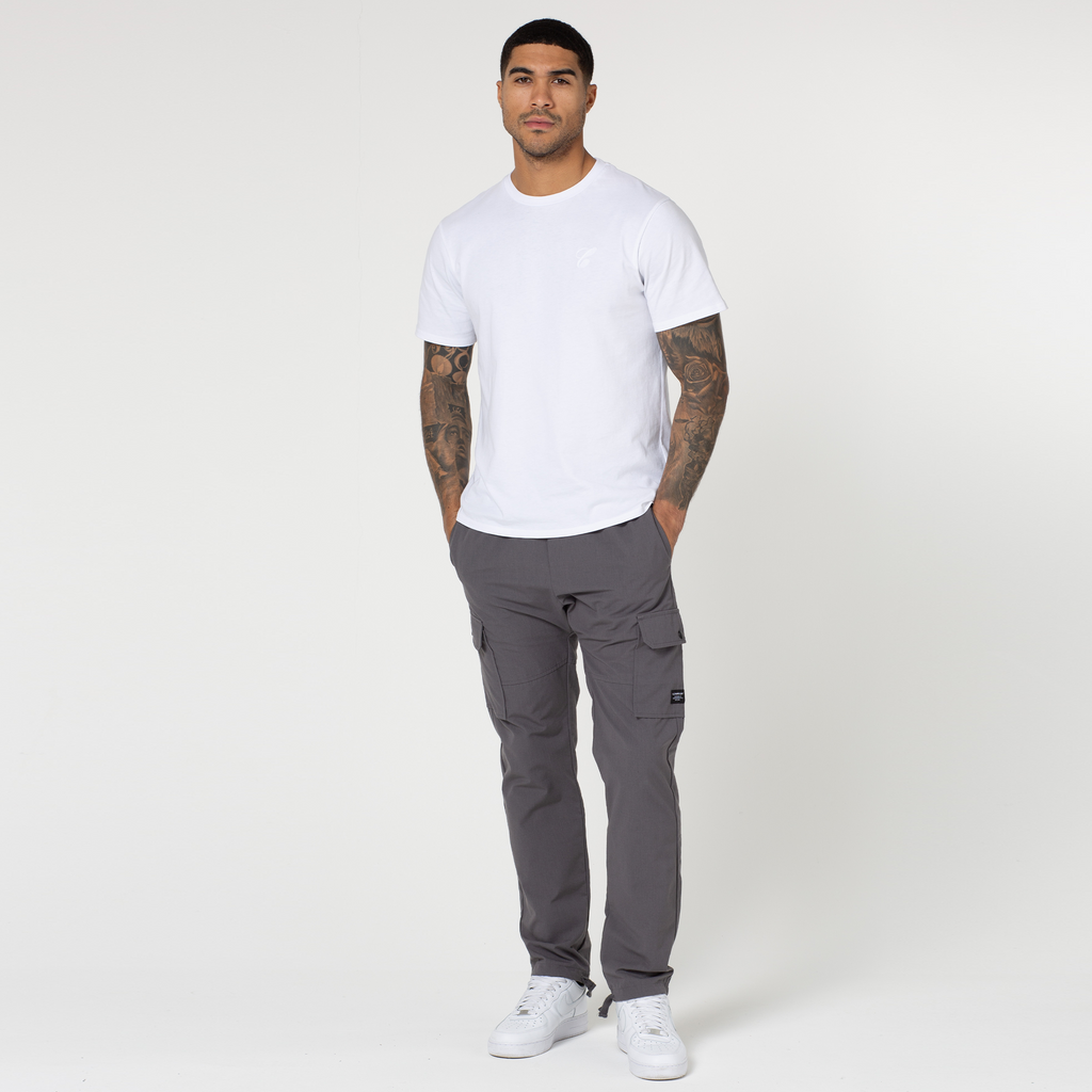 Model wearing charcoal grey utility trousers with open hem styled with white top and shoes