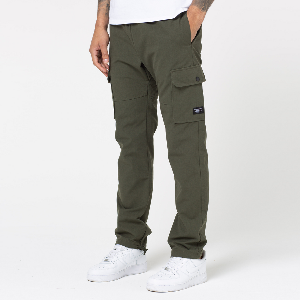 Male model wearing khaki men's cargo pants that are open hem styled with white trainers