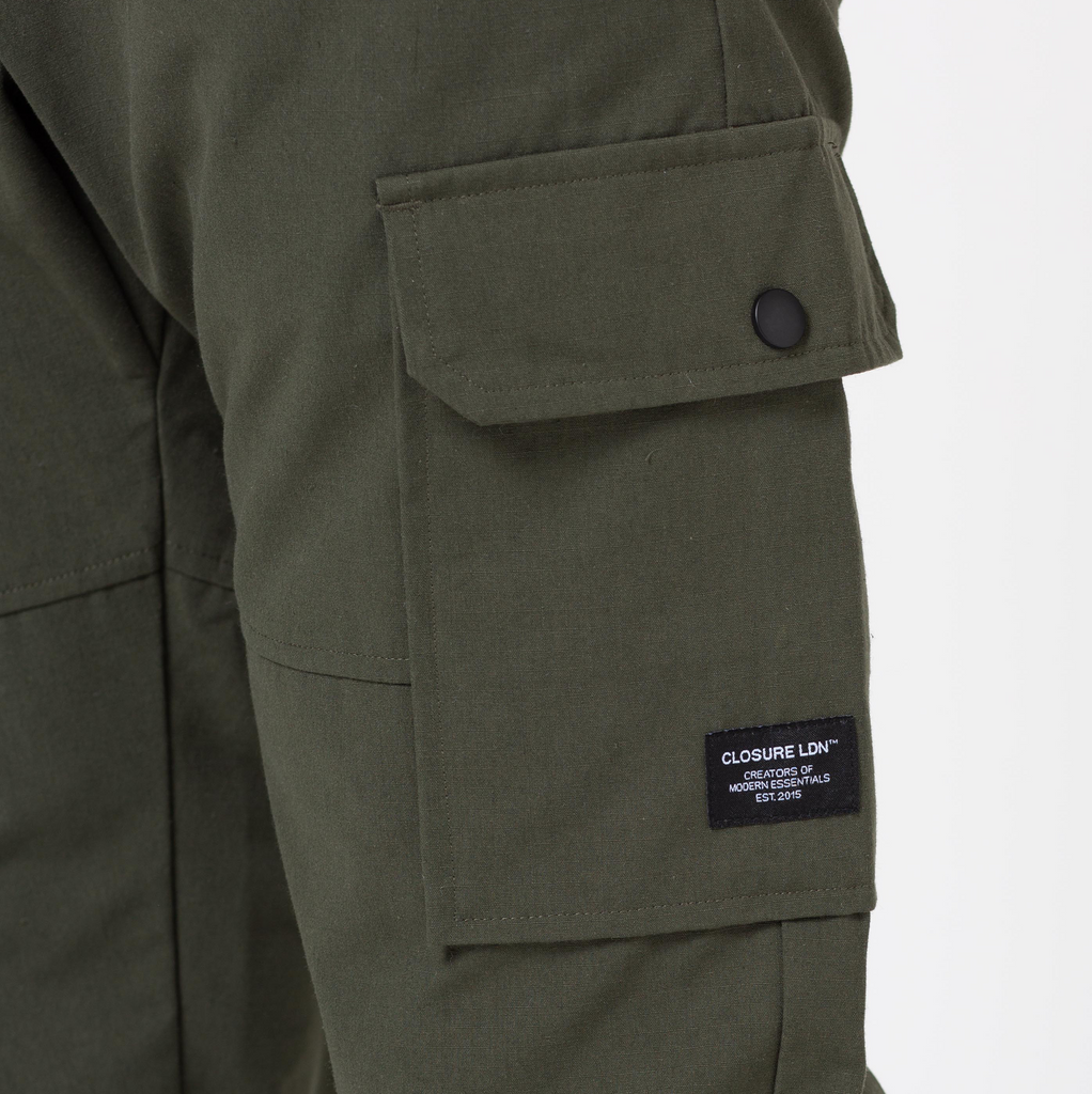 Close up of green utility trousers pocket showing black "Closure LDN" logo