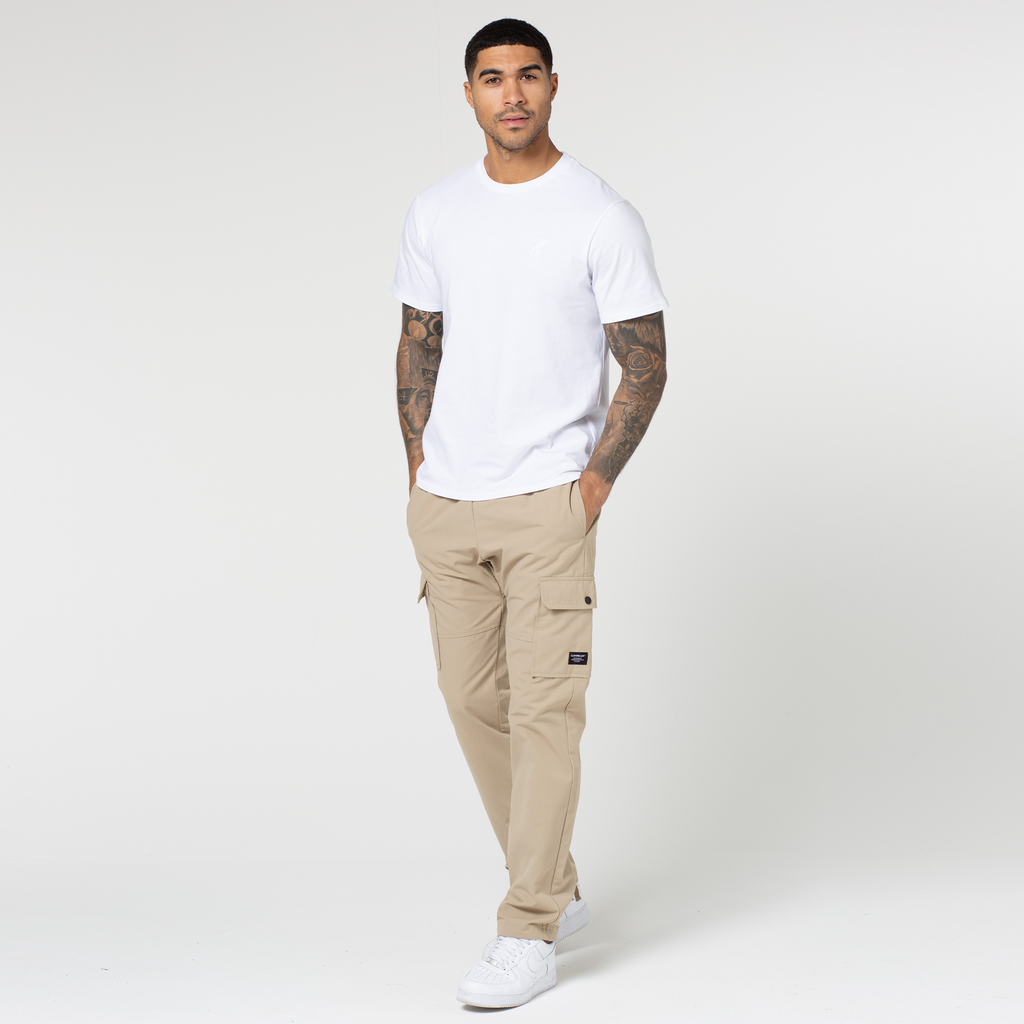 Model wearing sand coloured cargo pants with open hem styled with white top and trainers