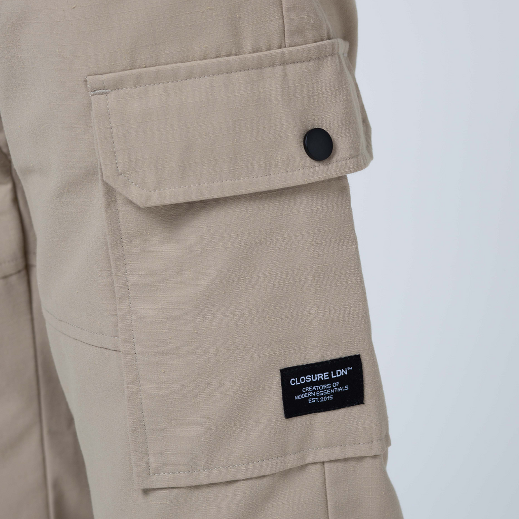 Close up of utility cargo pants pocket with black popper button and black patch tag