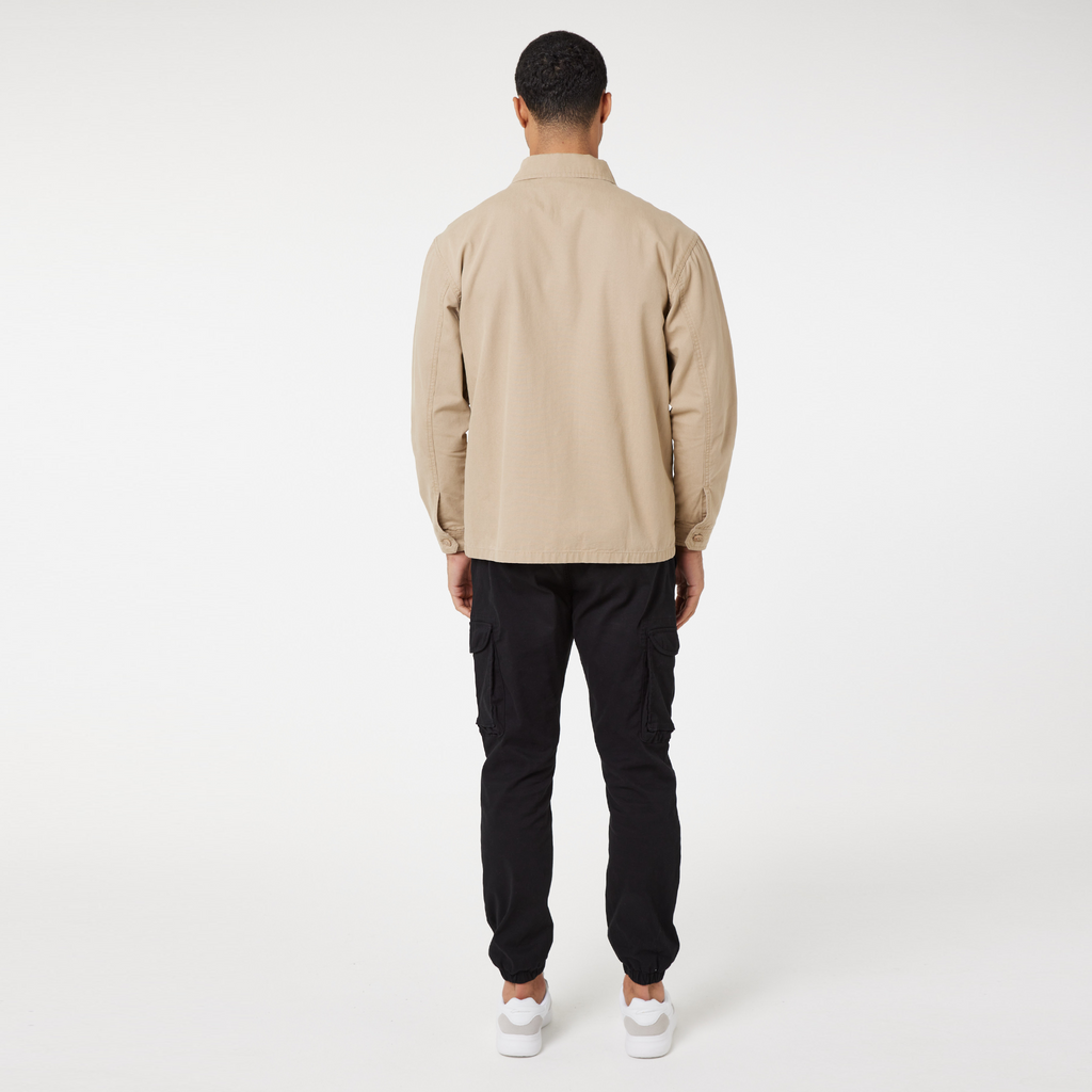 Back profile of men's overshirts jacket in beige paired with black pants