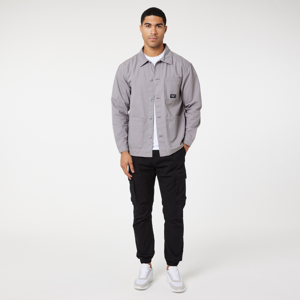 Model wearing light grey overshirt jacket over a white top paired with black cargo trousers