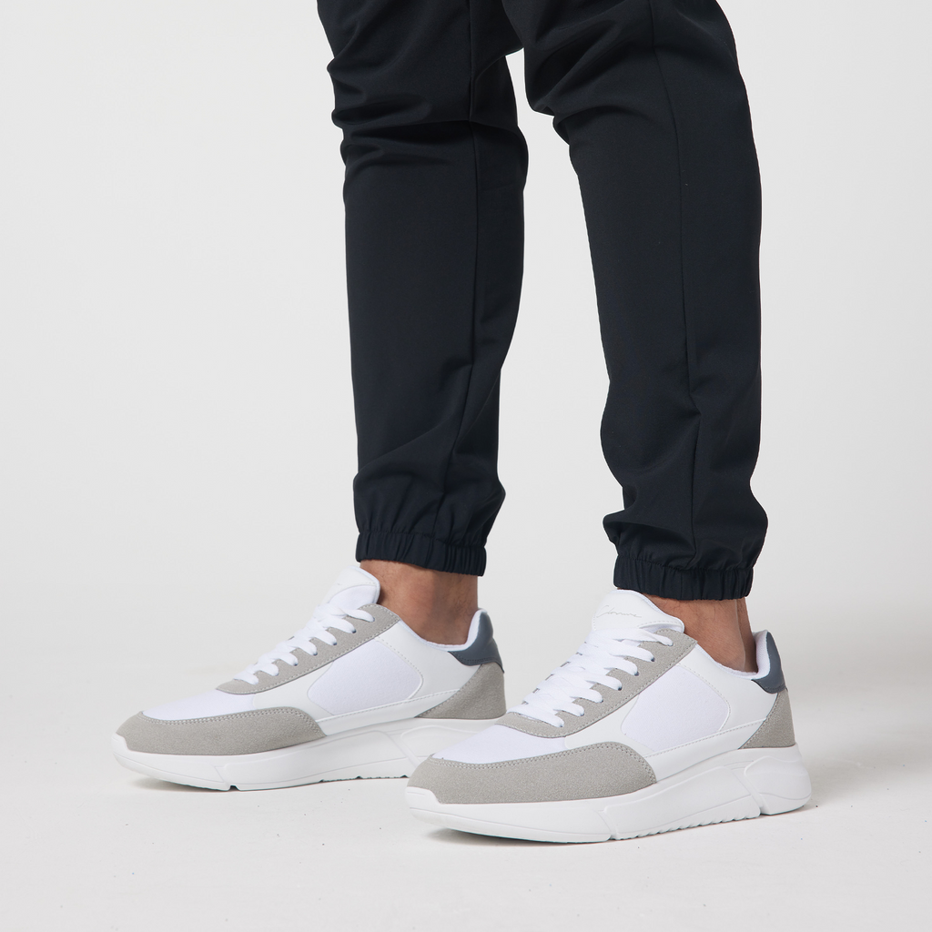 Close up picture of black cuffed men's cargo trousers paired with white and grey trainers