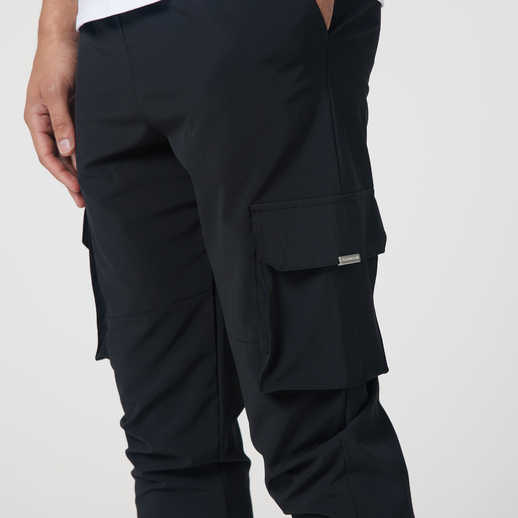 Close up picture of men's utility cargo pants in black with grey label attached to pocket