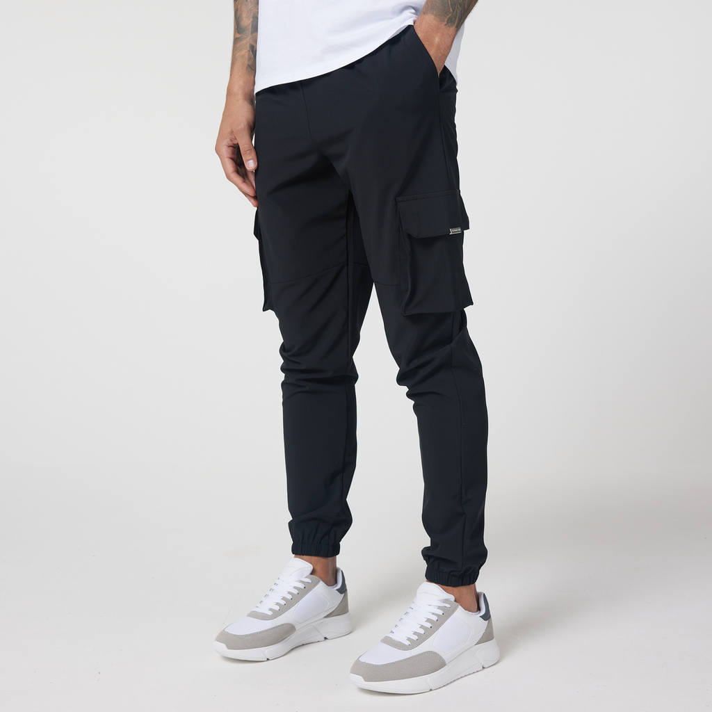 Black men's utility trousers with cuffed feature and two pockets styled with casual men's trainers