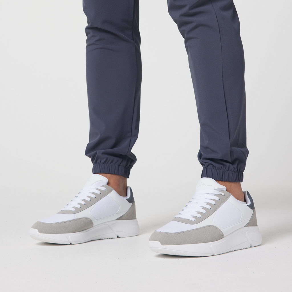 Close up of the men's cuffed cargo trousers in charcoal grey styled with white grey trainers