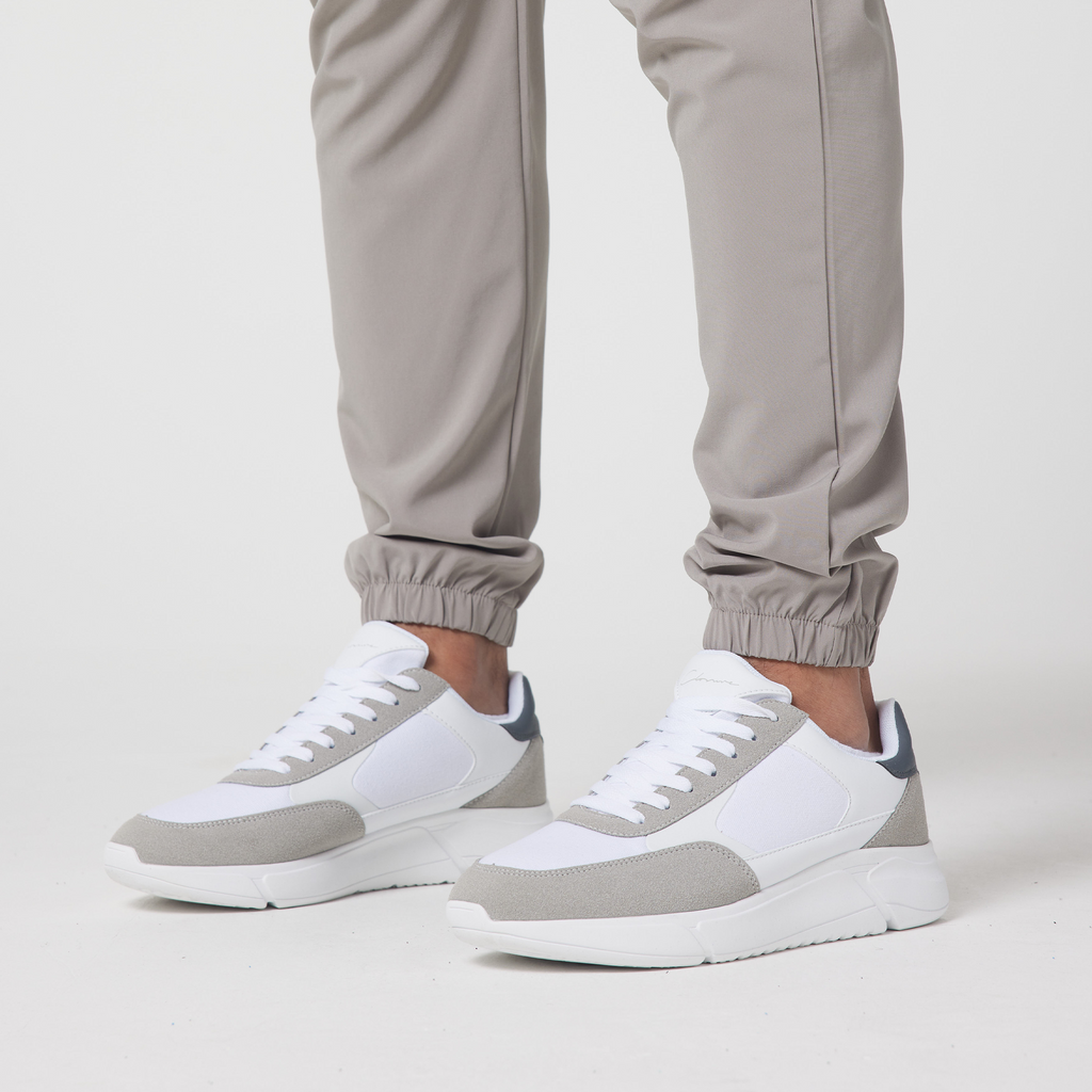 The bottom part of the cuffed men's utility cargo trousers styled with white and grey casual trainers