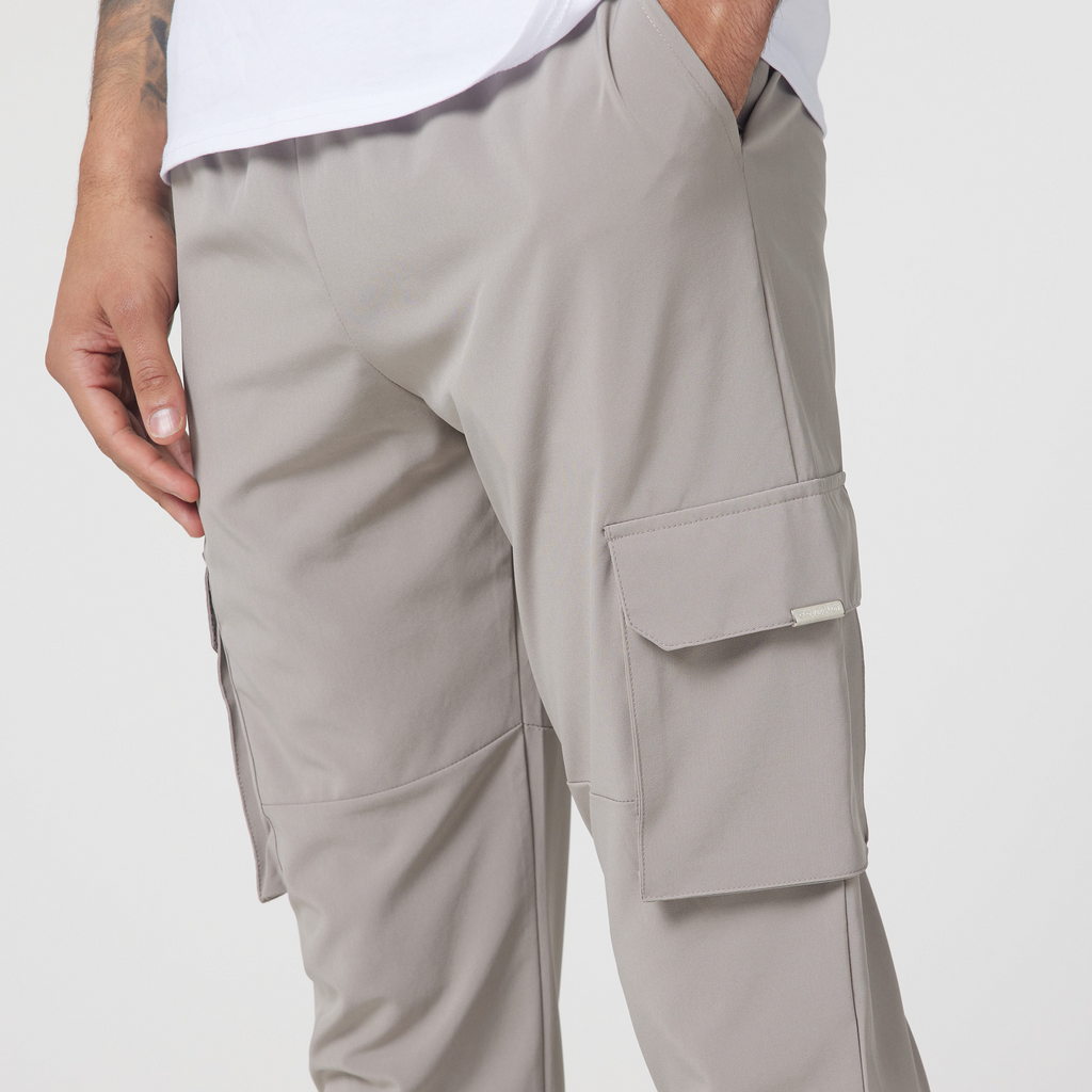 Close up of men's cargo pants pockets in the colour stone with a logo tag on the pocket