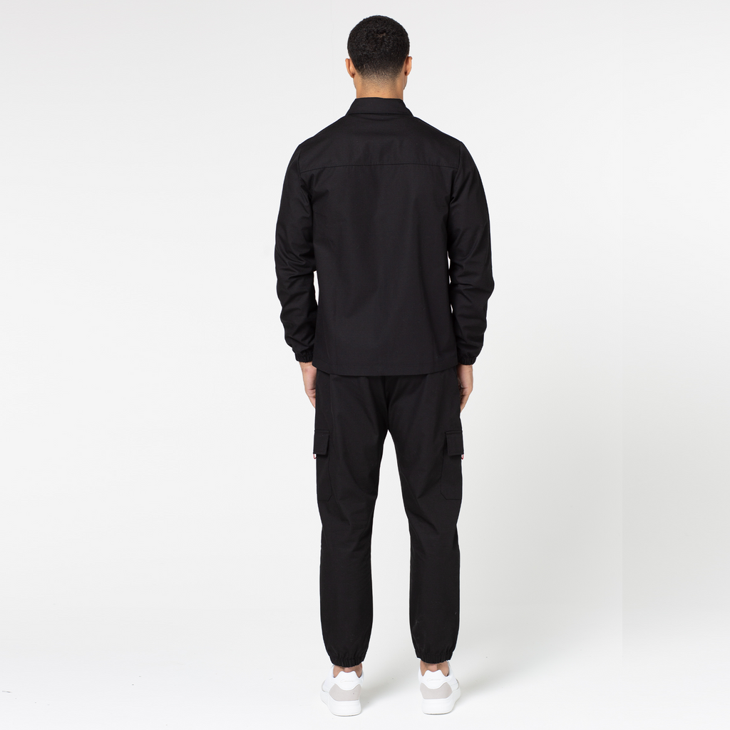 Back profile view of tech utility cargo pants with matching overshirt and white trainers