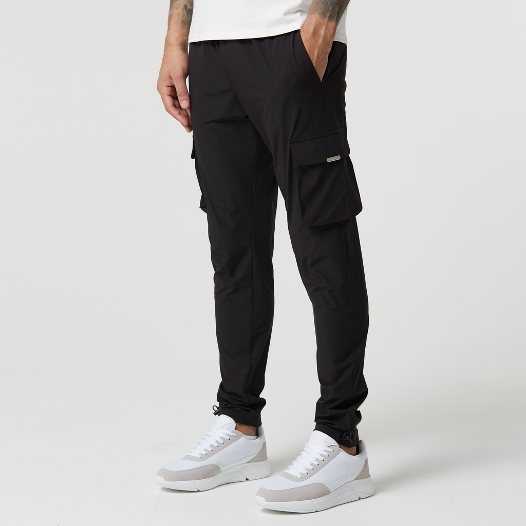 Black tech men's cargo pants with adjustable cuffs paired with white and grey trainers