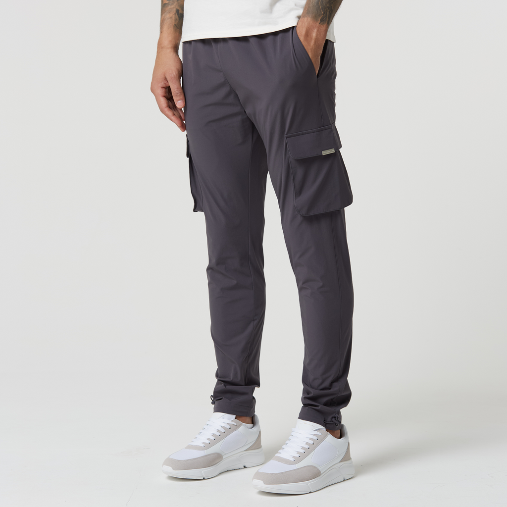 Dark grey men's cargo pants with adjustable cuffs paired with white trainers