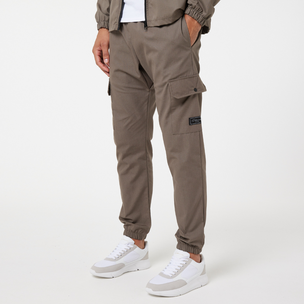 Utility trousers in ash brown that are cuffed at the ankle styled with white and grey trainers