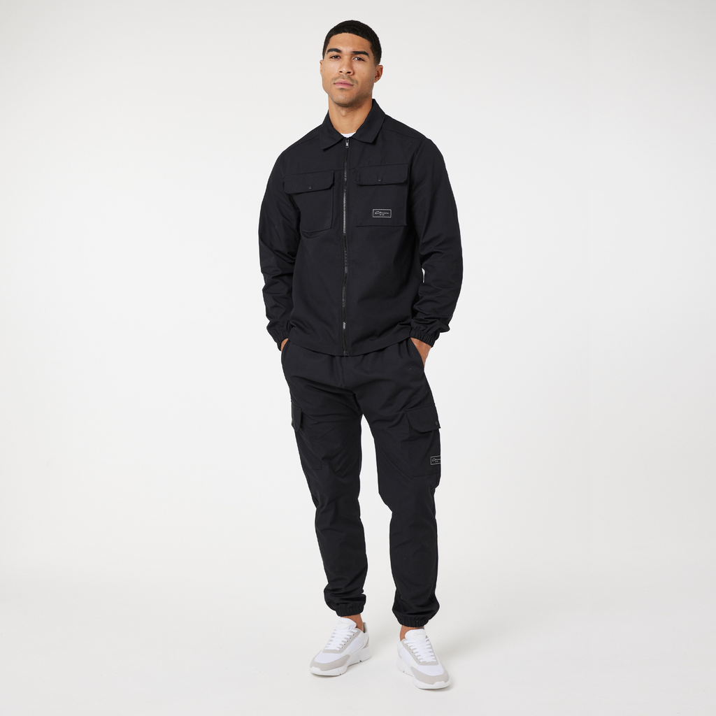 Men's zip up overshirt in black paired with matching cargo pants and casual trainers