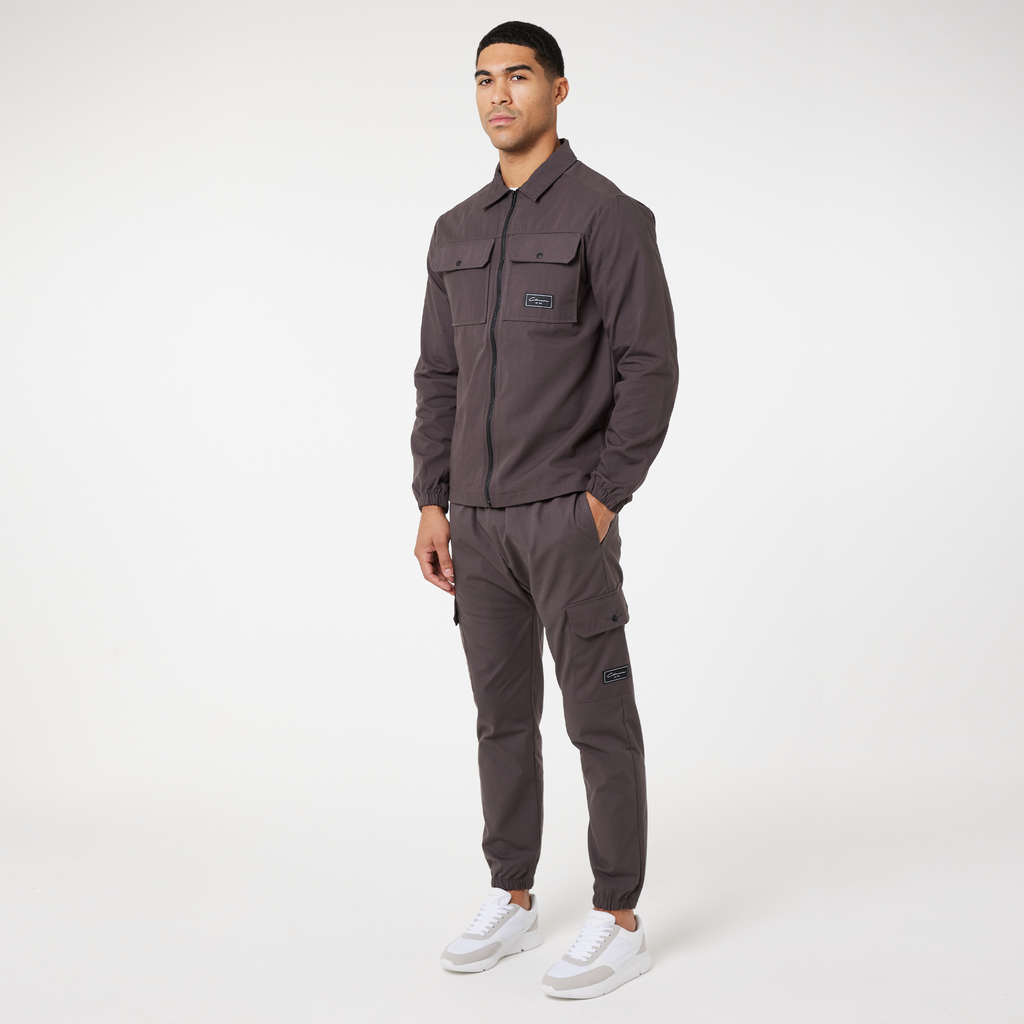 Model wearing brown utility overshirt jacket with matching utility trousers and white trainers