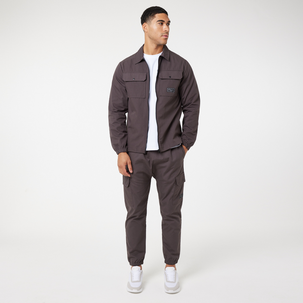 Brown men's zip overshirt jacket styled on model with white tee, matching cargo trousers and white shoes