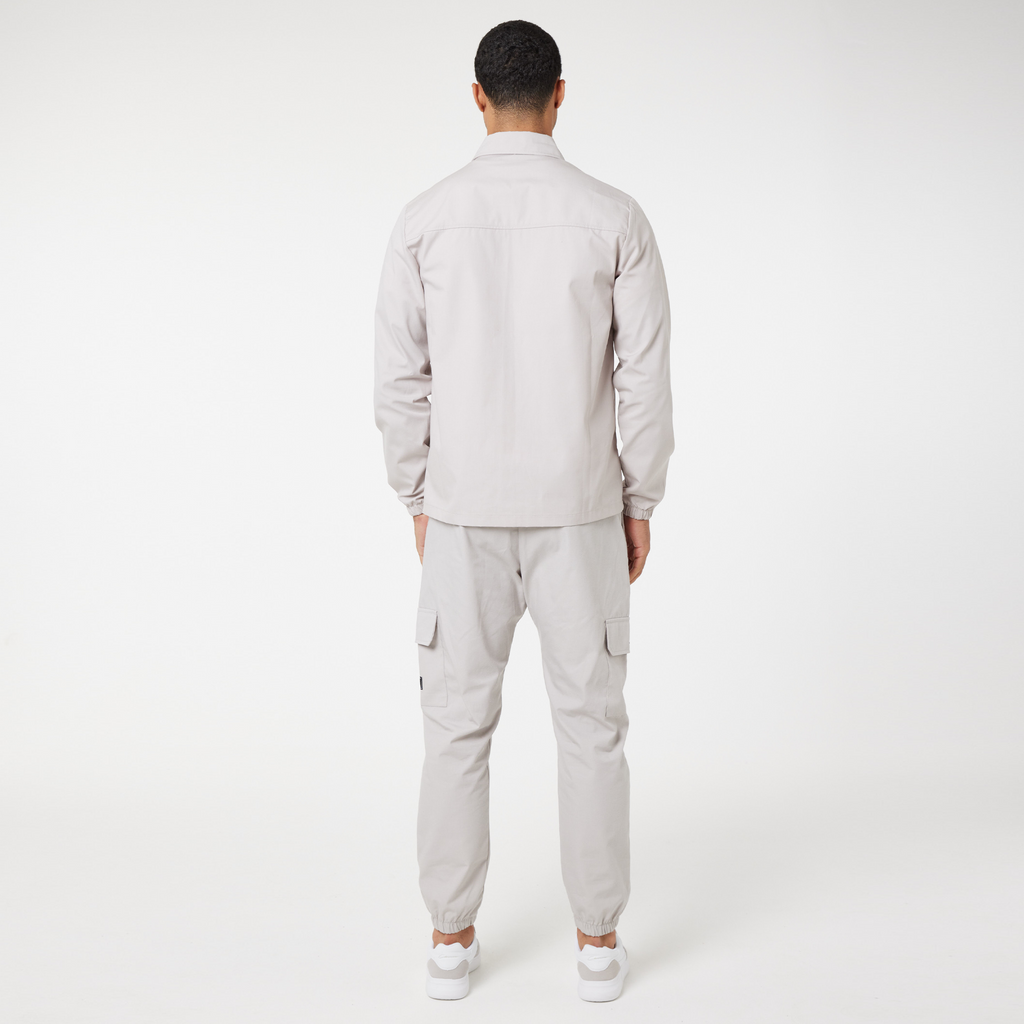 back view of model wearing chalk men's cargo trousers with matching overshirt