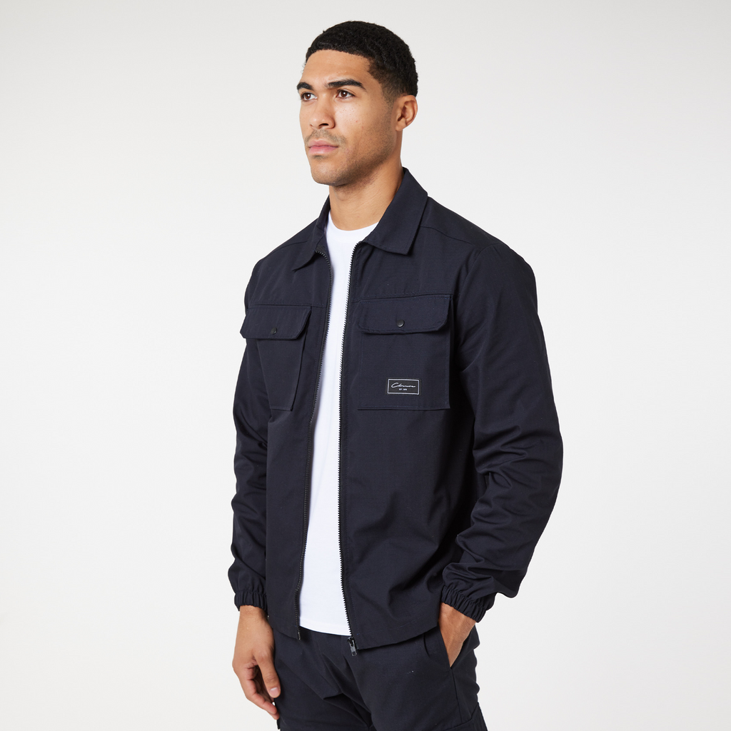 model wearing navy utility overshirt zip up jacket paired with white tee