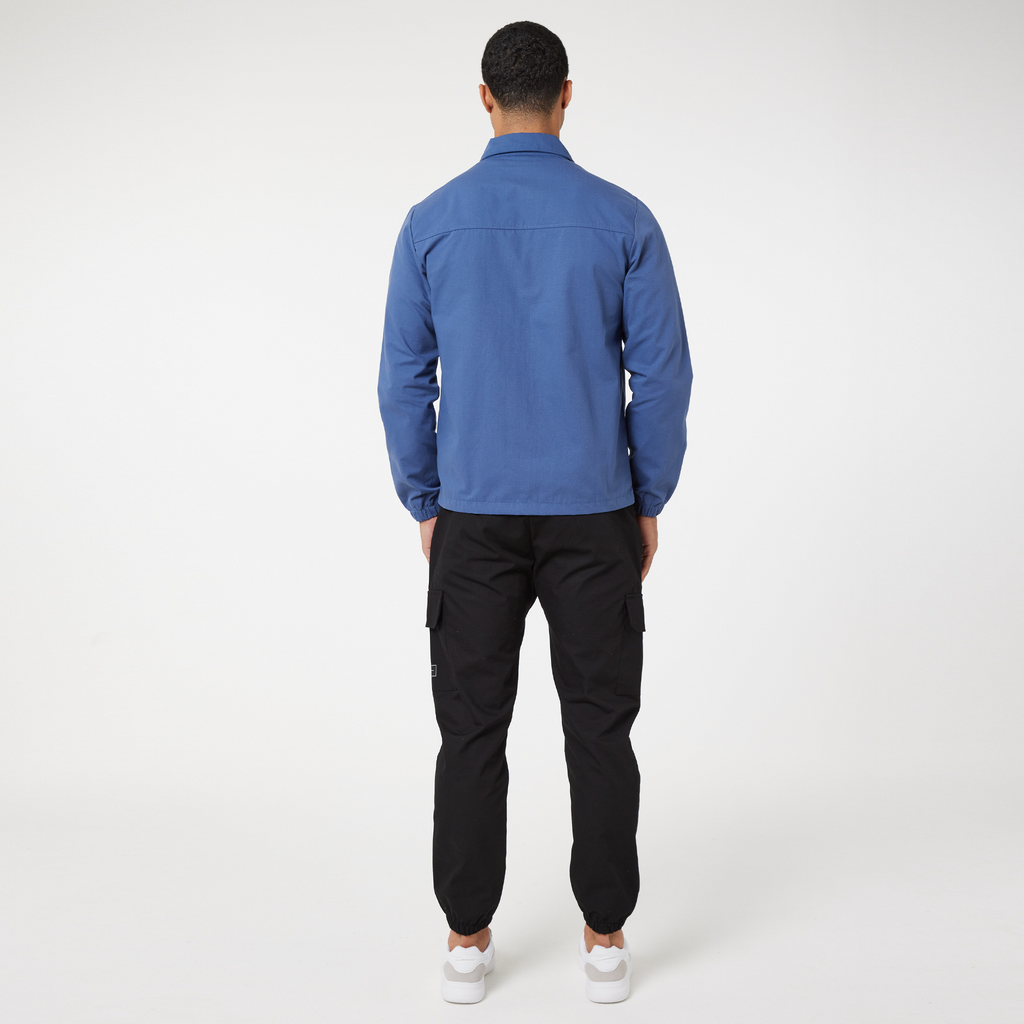 back profile of washed blue men's zip overshirt and black trousers
