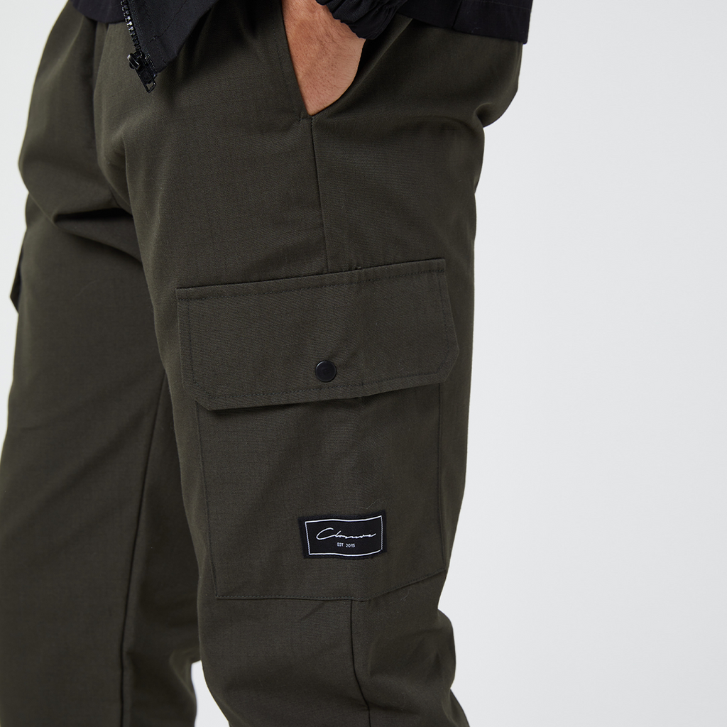 Close up of khaki pocket on men's cargo pants showing black button and black patch logo