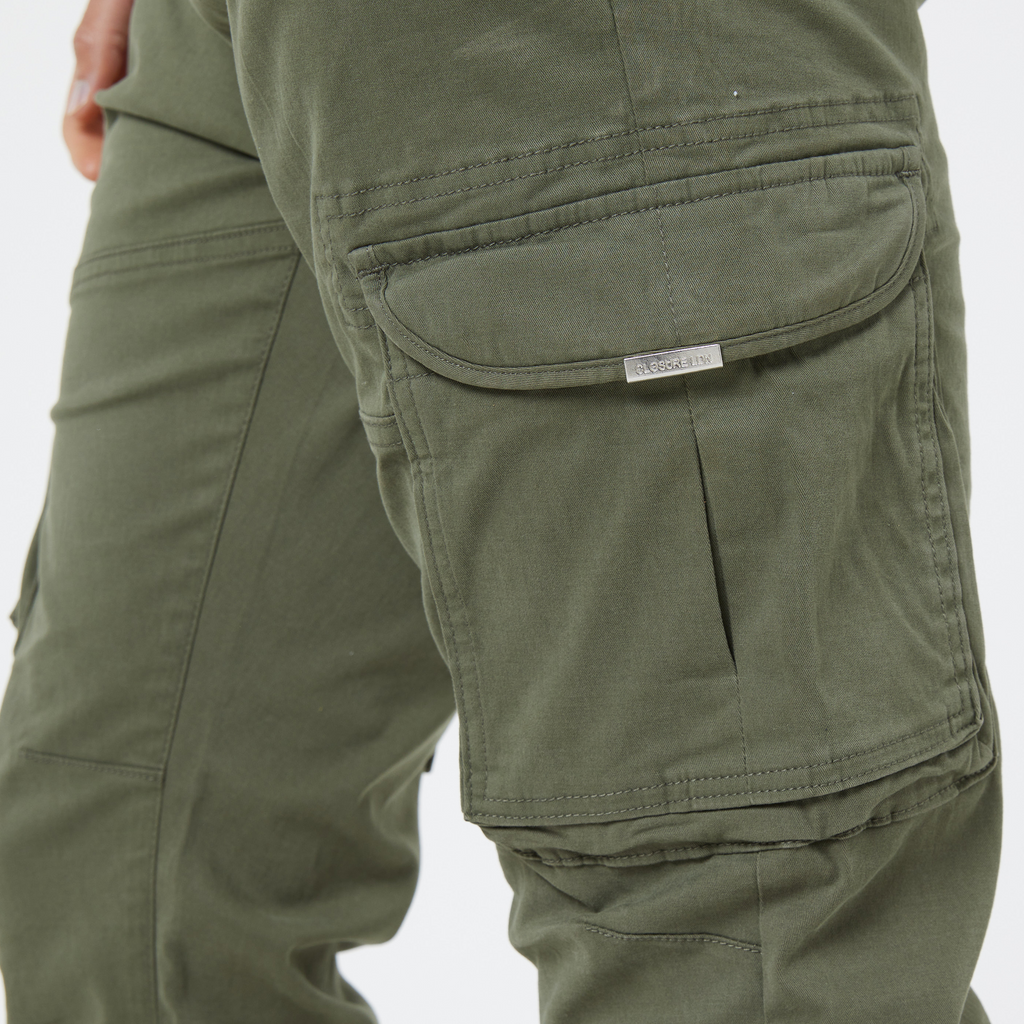 Zoomed in picture of green men's utility cargo pants pocket showing metal logo tag on pocket saying "Closure LDN"