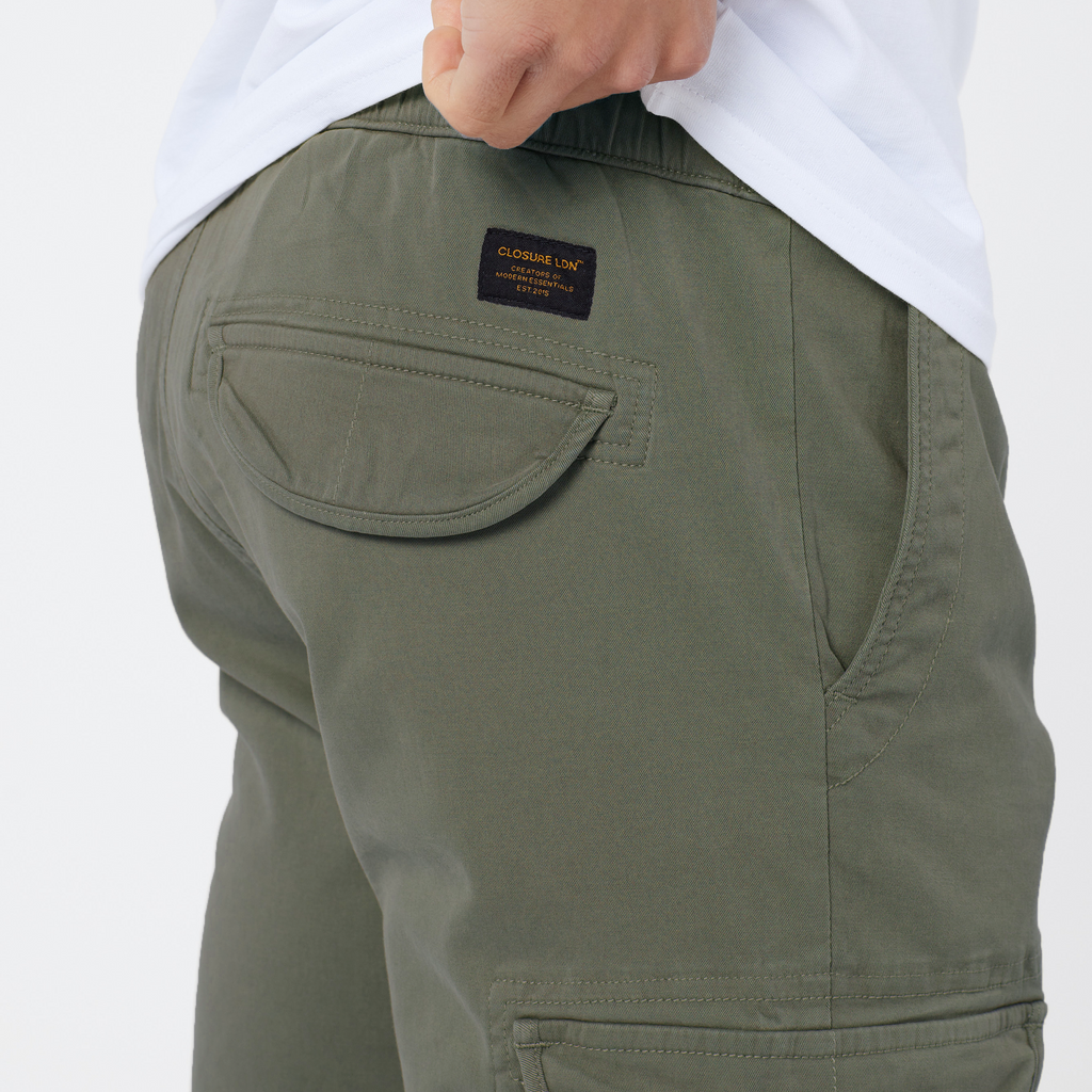 Back view of khaki cargo pants back pocket showing black and orange square patch logo